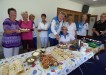 Mick cutting his cake at the ladies social day, with President Judy Hammond (kneeling) offering advice and lady bowlers supervising