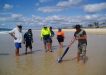 Tin Can Bay Fishing Club members being shown how to catch beach worms with local identity, Slippery Mick