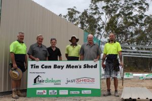 Holding the sign are Brian Linfield and Jamie Barnes form the Tin Can Bay Mens Shed, they are delighted to have the Just Sheds team on site