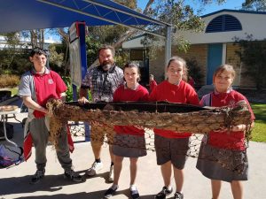 Ty-reece, Brent Miller (presenter), Allyra, Elsie and Alyssa hold a traditional canoe during NAIDOC celebrations last month