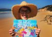 Dr Suzie with her first picture book at Rainbow Beach