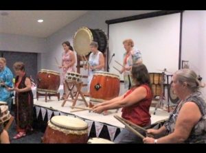 The Japanese Drumming Group with QCWA members, Lorraine and Irene, trying out the drums!
