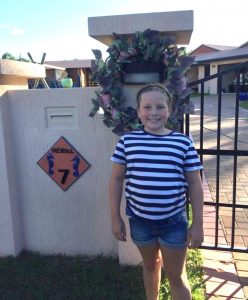 Mia Reibel in front of the wreath she made with her mother Rebecca for the Anzac Day driveway service