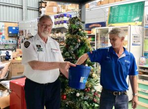 Commander John Macfarlane and Mark from Mitre 10 drawing the Christmas raffle winners for the Tin Can Bay Coastguard