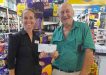 Kristy from Rainbow Beach IGA presenting Tony with a donation cheque