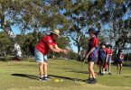 Junior Golfing Coordinator Janet Reibel helps Mary with her putting. Photo credit: Tin Can Bay P-10 School